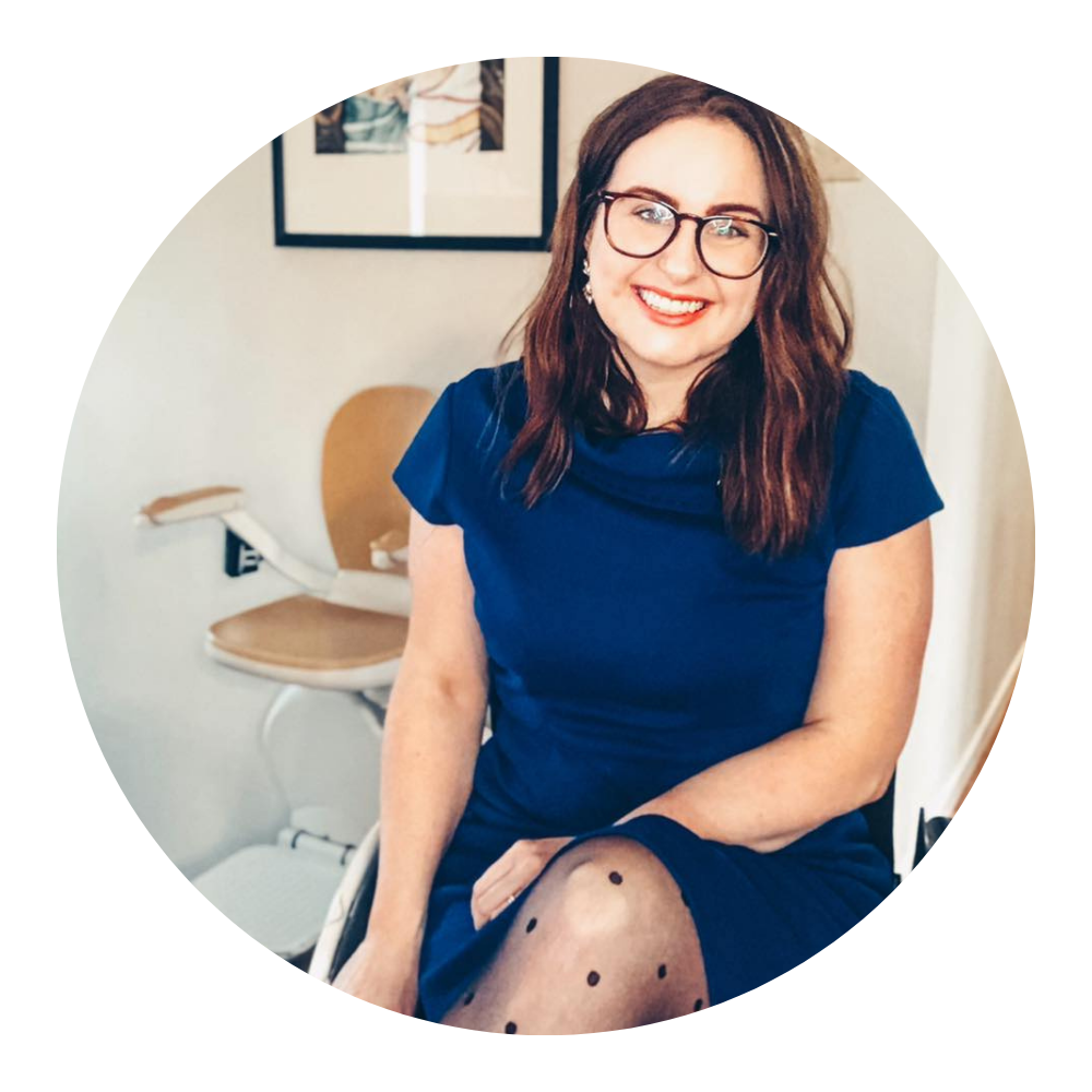 photo of lisa walters in a blue dress sitting in her wheelchair next to her chair lift