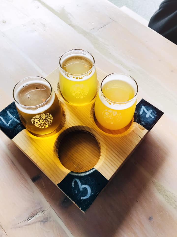 A flight of 3 beer on a wooden holder.