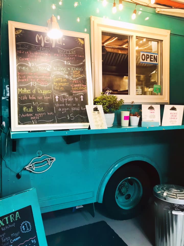 A teal coloured food truck with a chalkboard menu sign on the side.