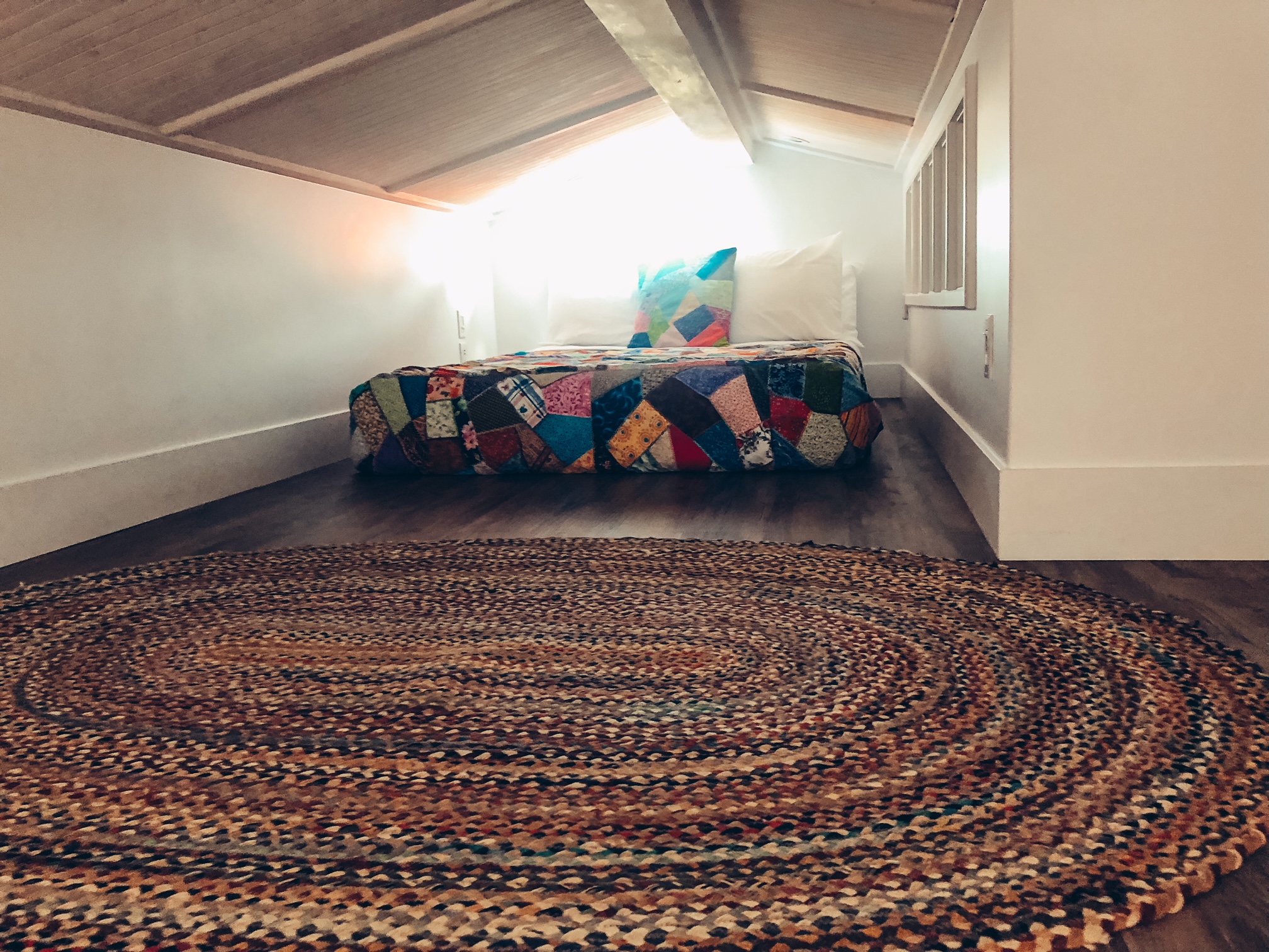 A photo of the double bed on the floor of the loft with a rug in front of it.