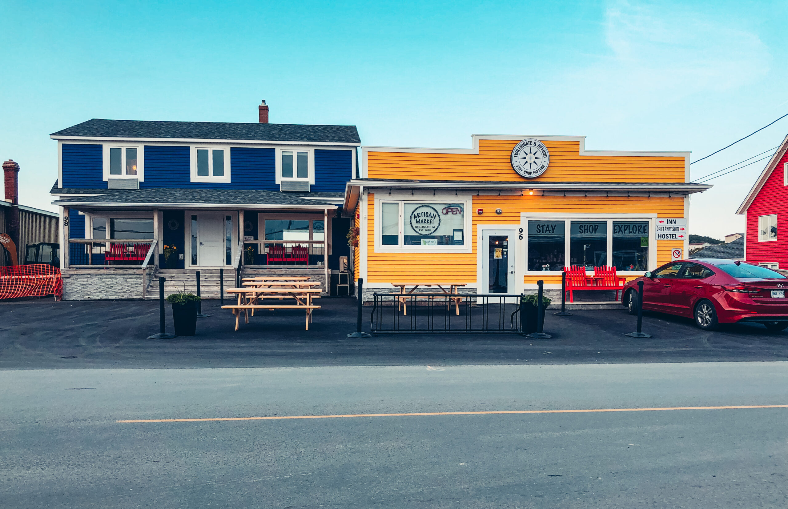 A photo of 2 buildings side by side in downtown Twillingate. There is a blue house which is another vacation rental from Twillingate and Beyond, and next to it is a yellow building which houses their artisan market on the front and the Drift Away Suite in the back.